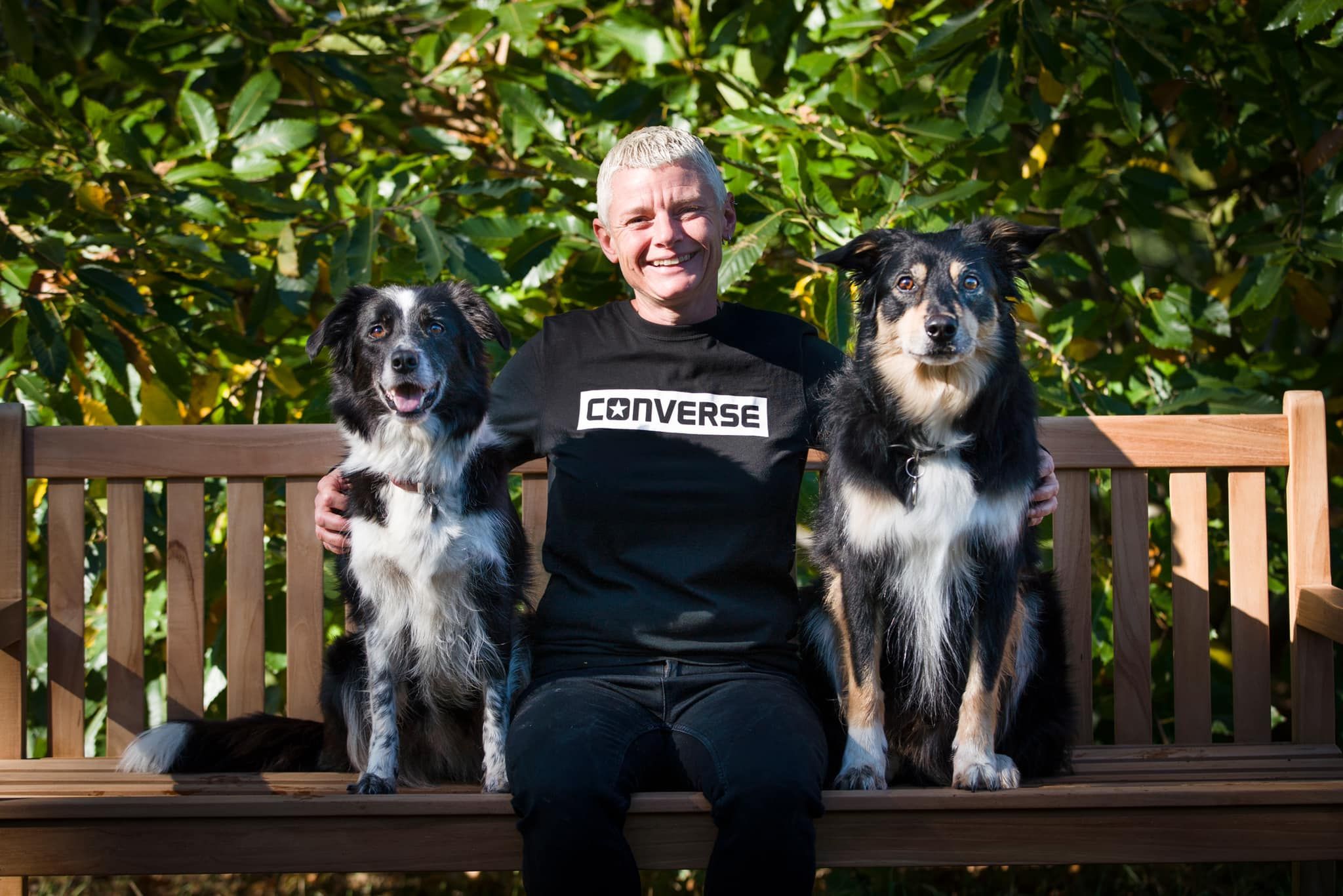 Di on a bench with two dogs online dog training course